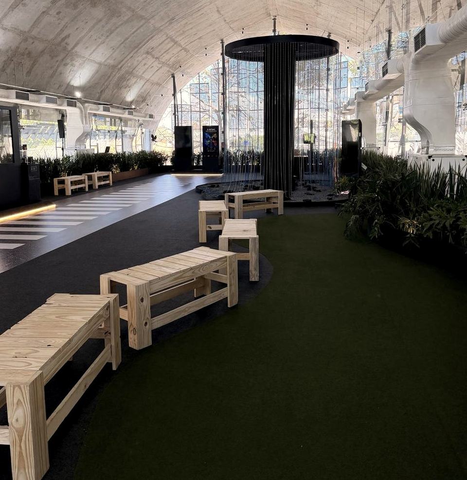 Salão em arco do Centro Sebrae, com bancos de madeira e vegetação ao longo do percurso